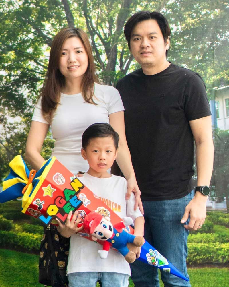 A family posing for a picture with a boy holding a cone that says mario on it.