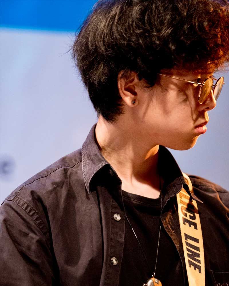 A man wearing glasses and a black shirt with a yellow strap that says off line