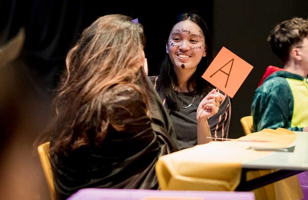 A woman is holding a card with the letter a on it.