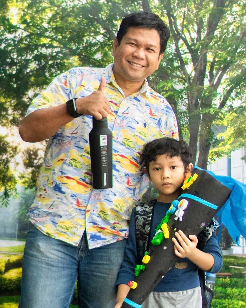 A man and a boy are standing next to each other holding a bottle and a toy.