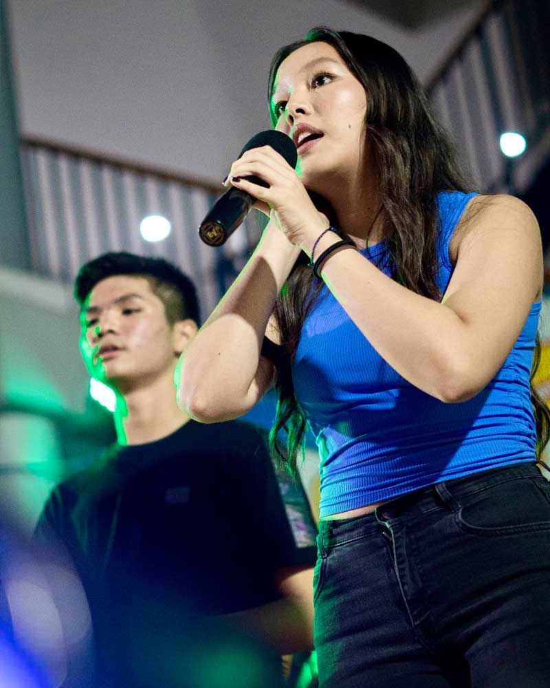 A woman is singing into a microphone while standing next to a man.