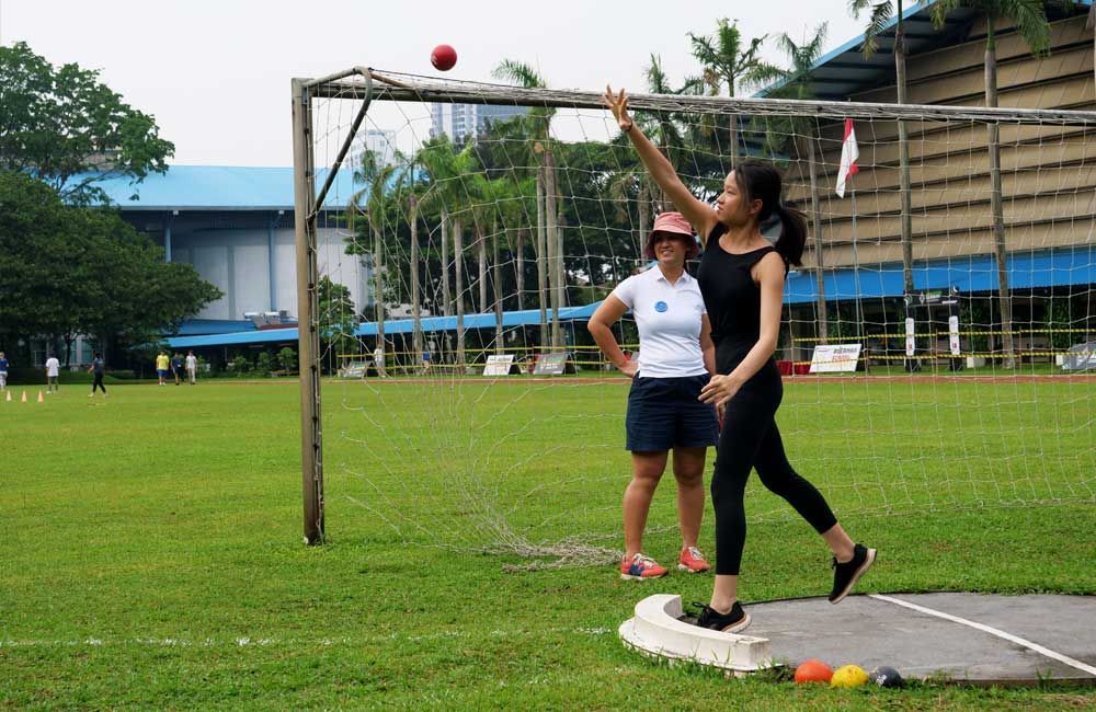 Two women are throwing a ball in a field.