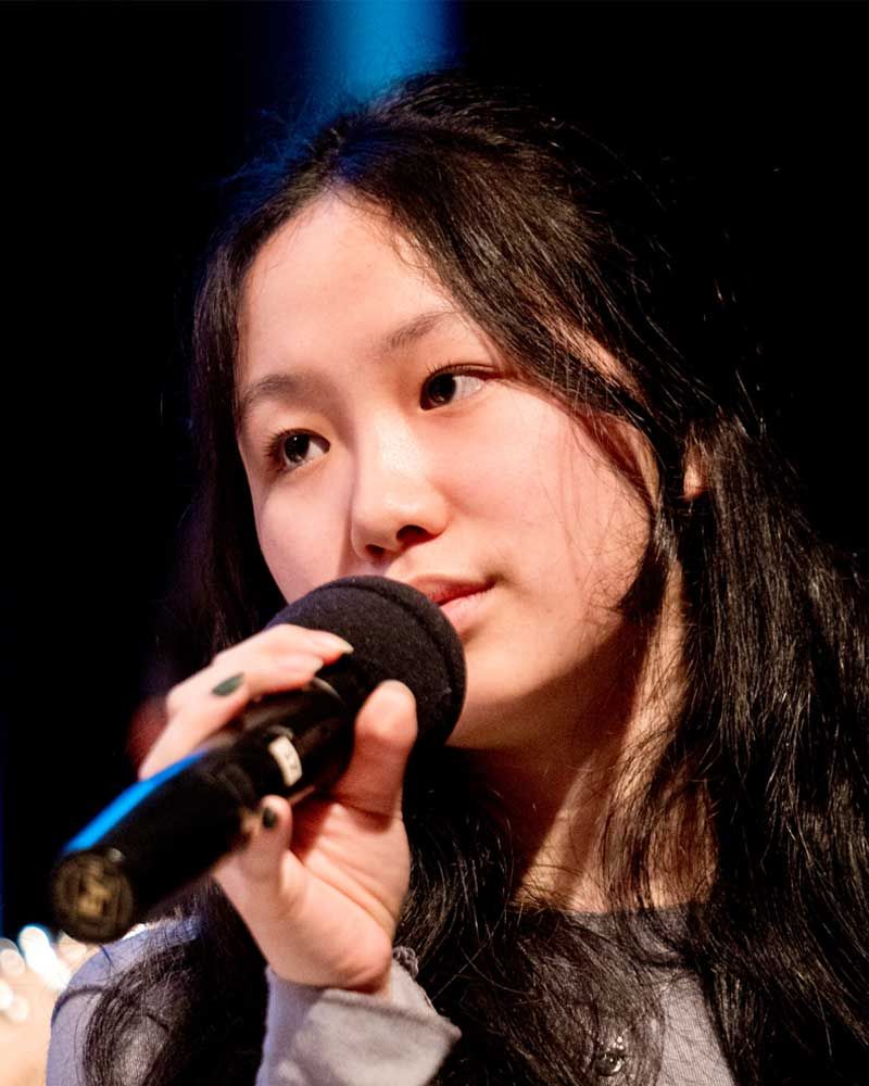A young woman is singing into a microphone.