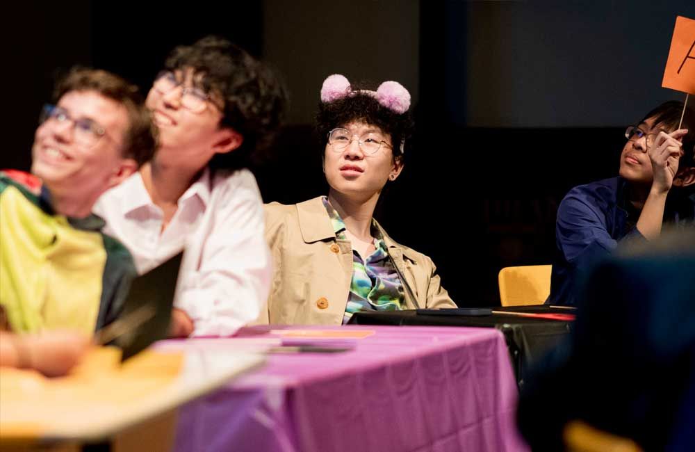 A group of people are sitting at a table holding signs.