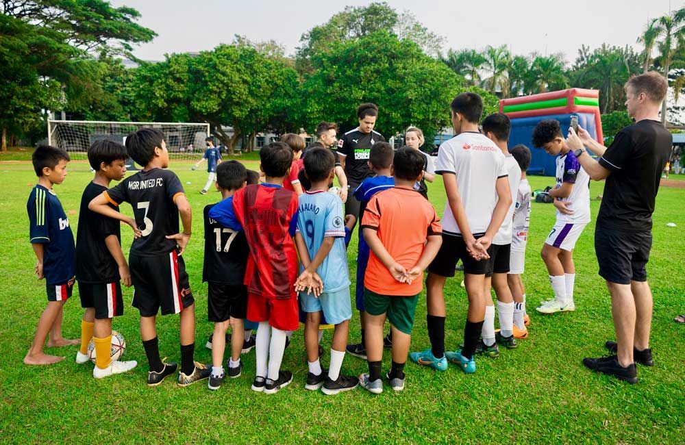 A group of young boys are standing in a circle on a soccer field.
