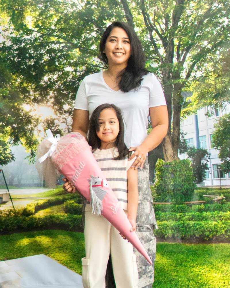 A woman and a little girl are standing next to each other holding a pink cone.