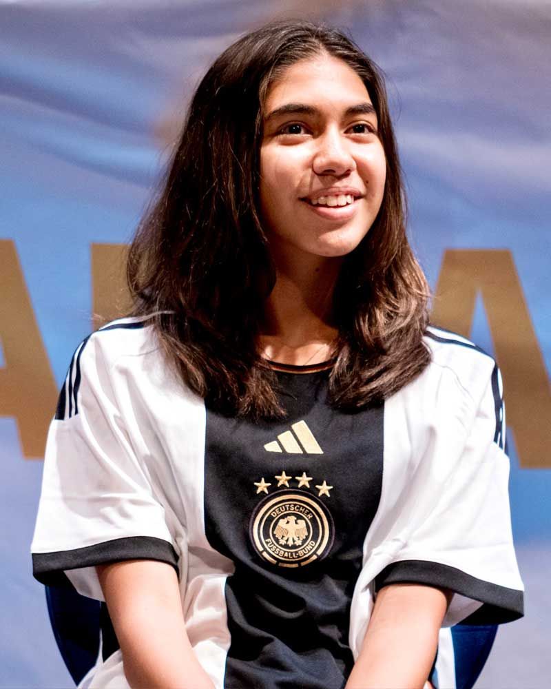 A girl wearing a black and white adidas shirt is smiling
