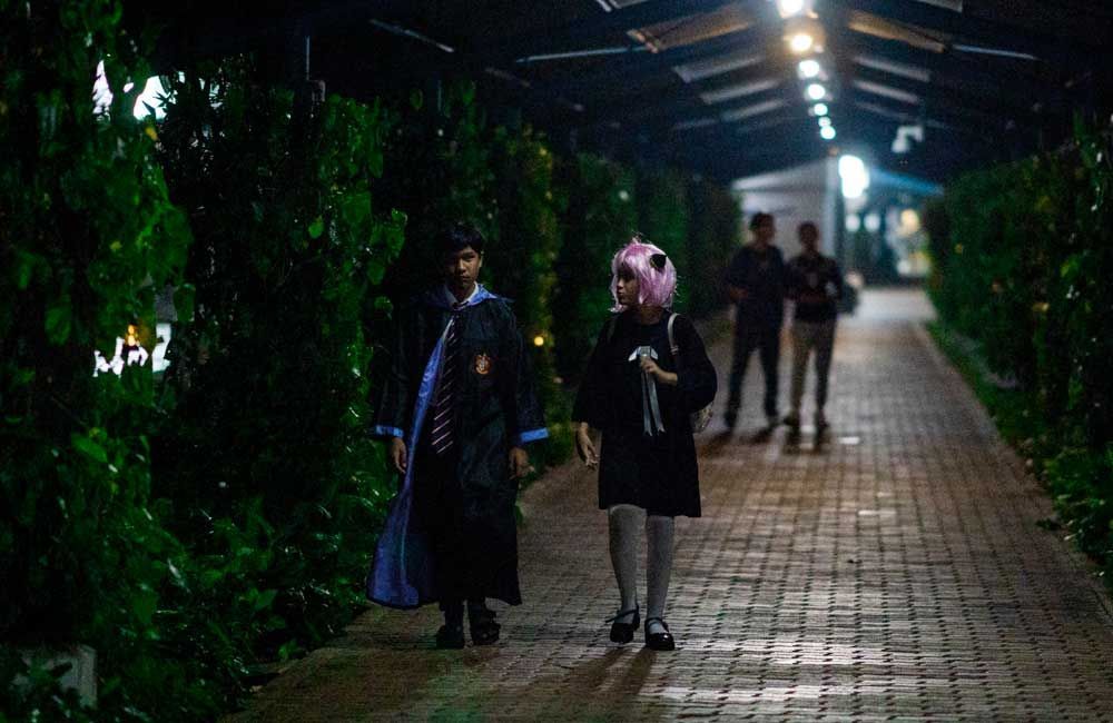 A group of people are walking down a brick walkway at night.