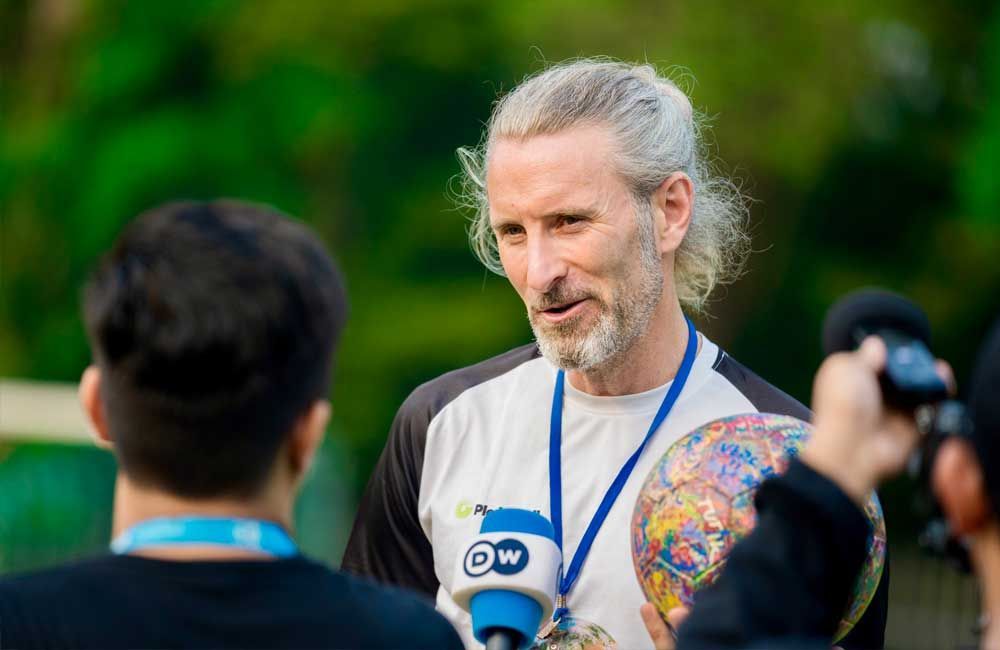 A man with a medal around his neck is talking into a microphone.