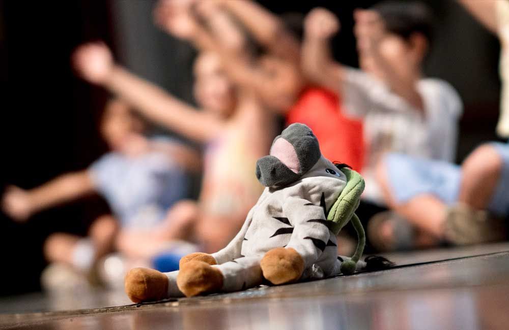 A stuffed animal is sitting on the floor in front of a group of children.