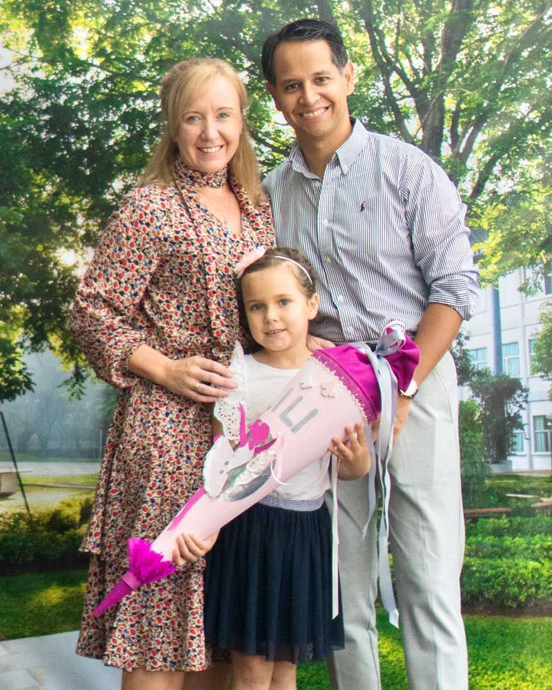A man and woman are standing next to a little girl holding a cone.