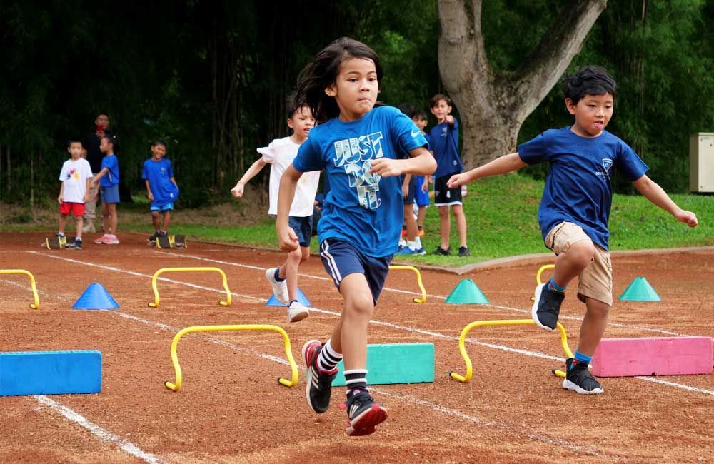 A group of young children are running on a track.