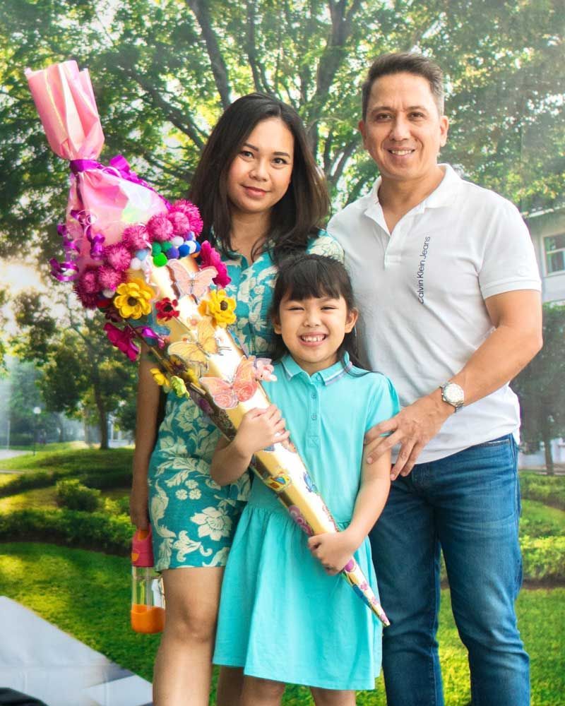 A family posing for a picture with a girl holding a bouquet of flowers.
