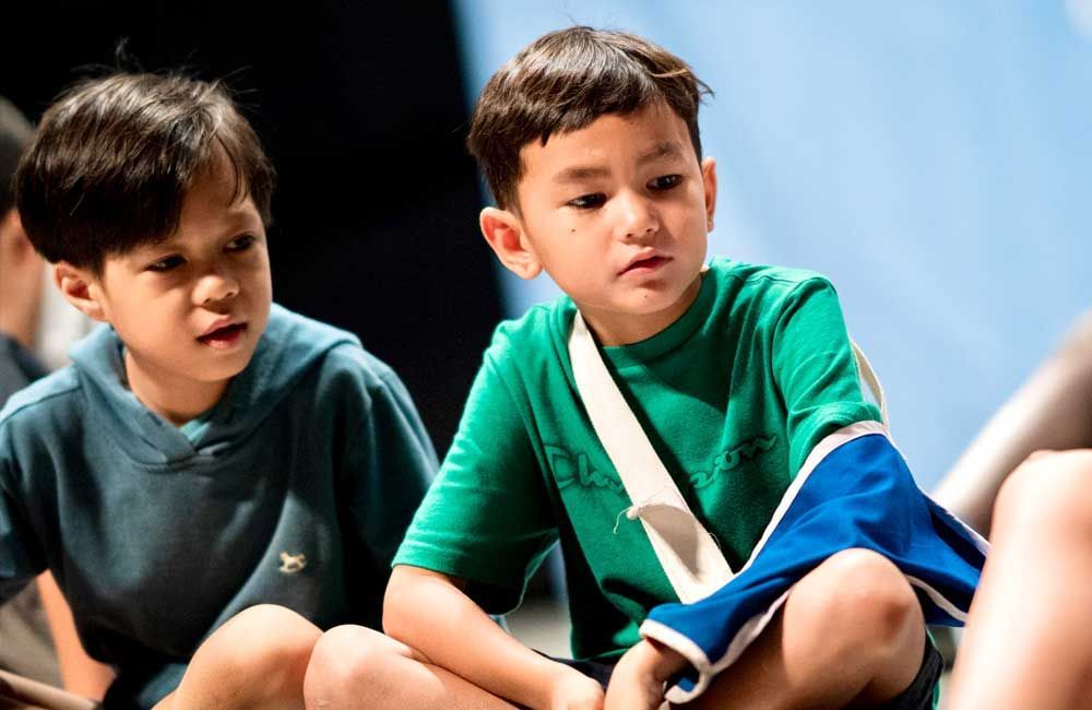 Two young boys are sitting next to each other on the floor.