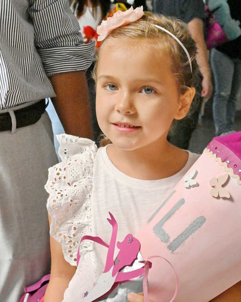 A little girl is holding a pink cone with the number 3 on it