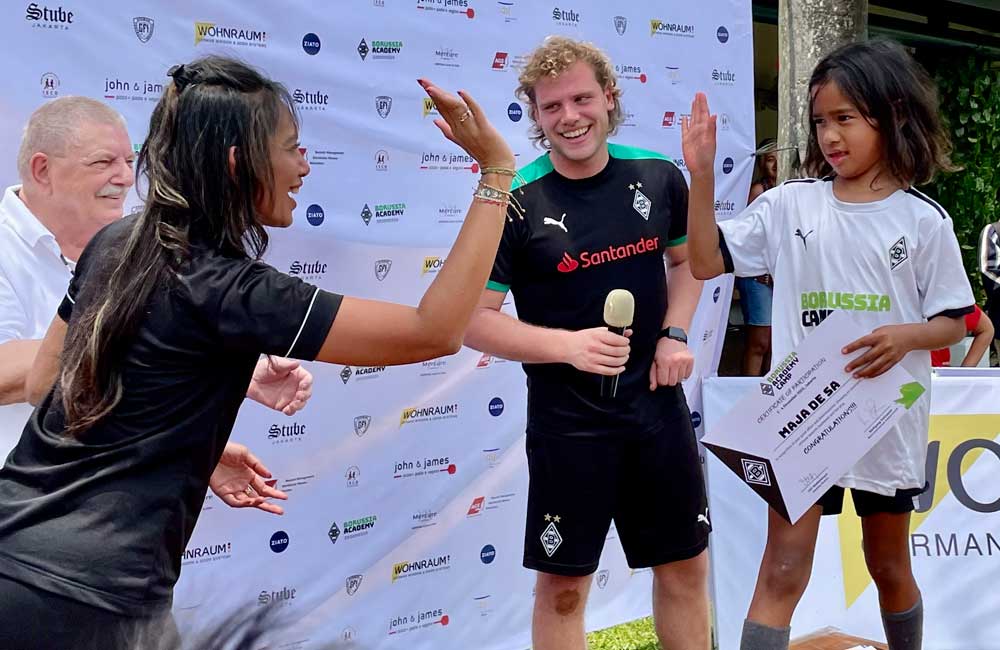 A woman is giving a high five to a young boy who is holding a certificate.