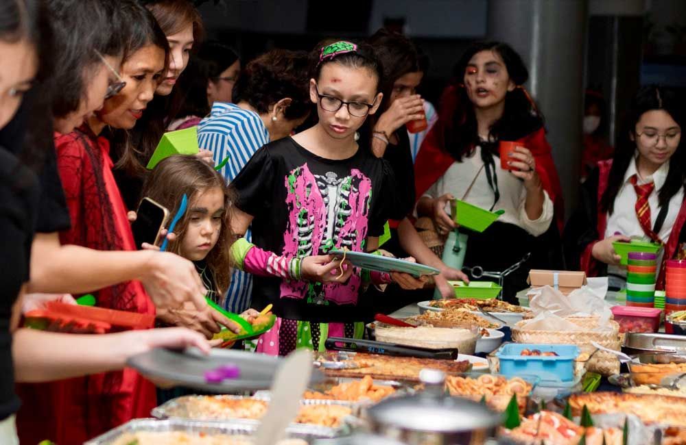 A group of people are standing around a table eating food.