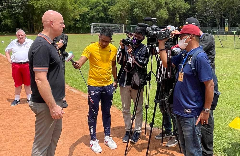 A group of people are standing on a field talking to each other.
