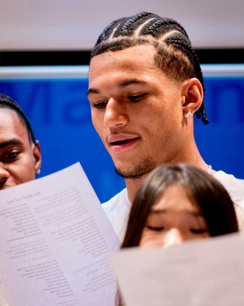 A man is reading a piece of paper in front of a group of people