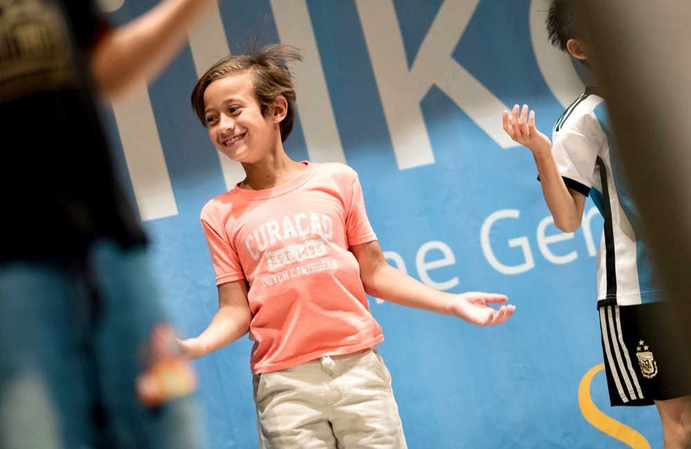 A boy wearing a pink shirt that says curaçao on it