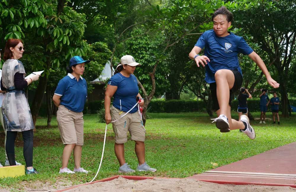 A boy is jumping in the air while a group of people watch.