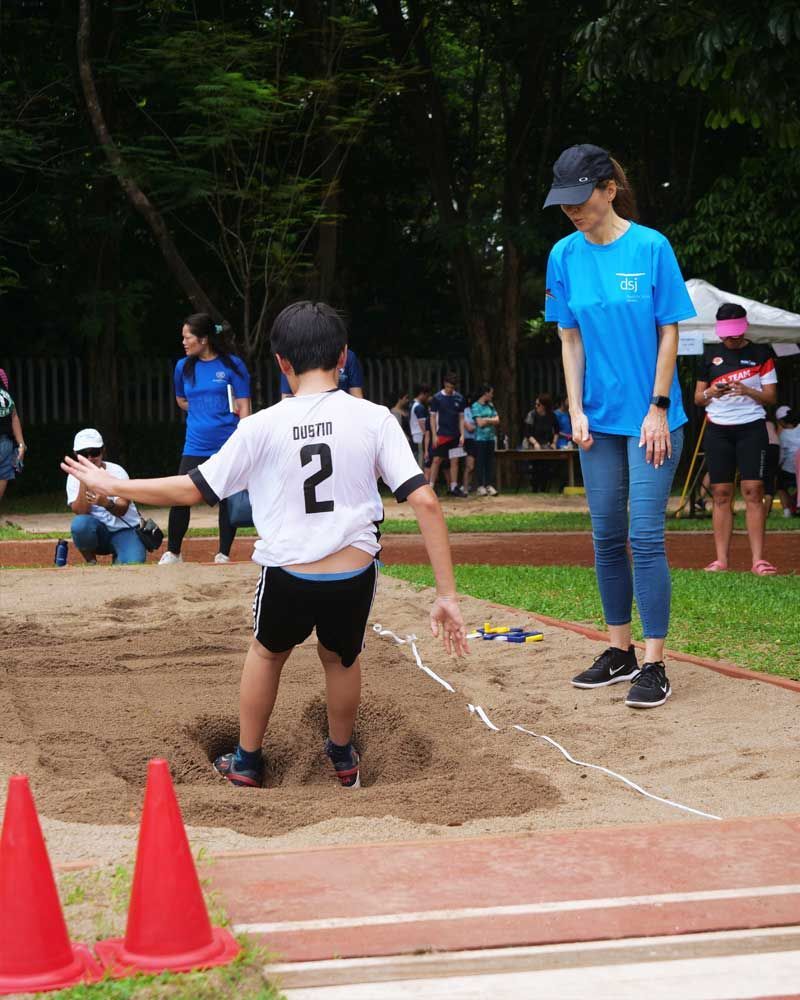 A boy wearing a number 2 shirt is jumping in the dirt.