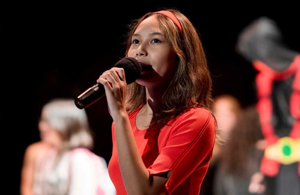 A woman in a red dress is singing into a microphone.