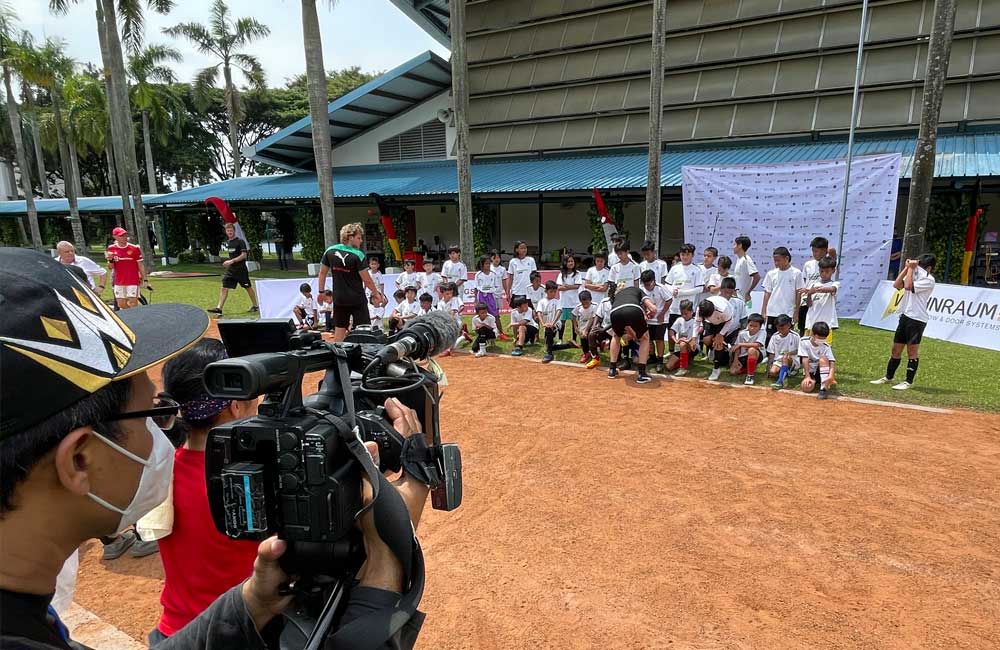 A man is holding a camera in front of a group of children.
