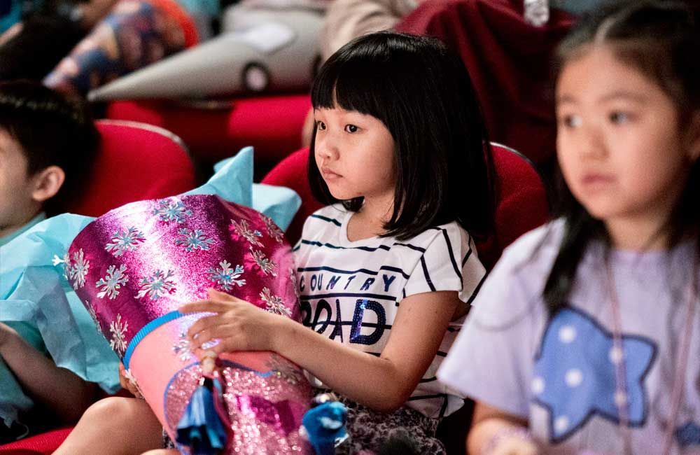 A group of children are sitting in a theater watching a show.