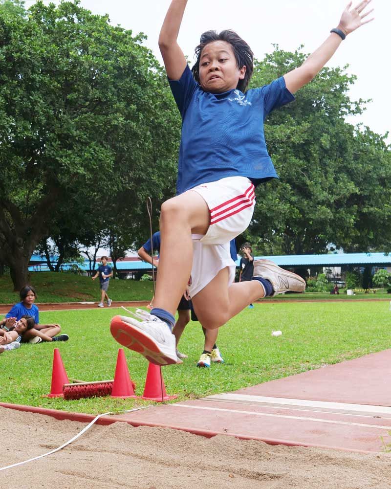 A young boy in a blue shirt is jumping in the air