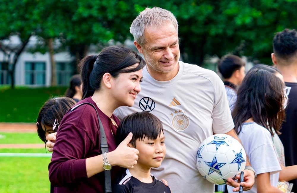 A man and woman are posing for a picture with a boy holding a soccer ball.