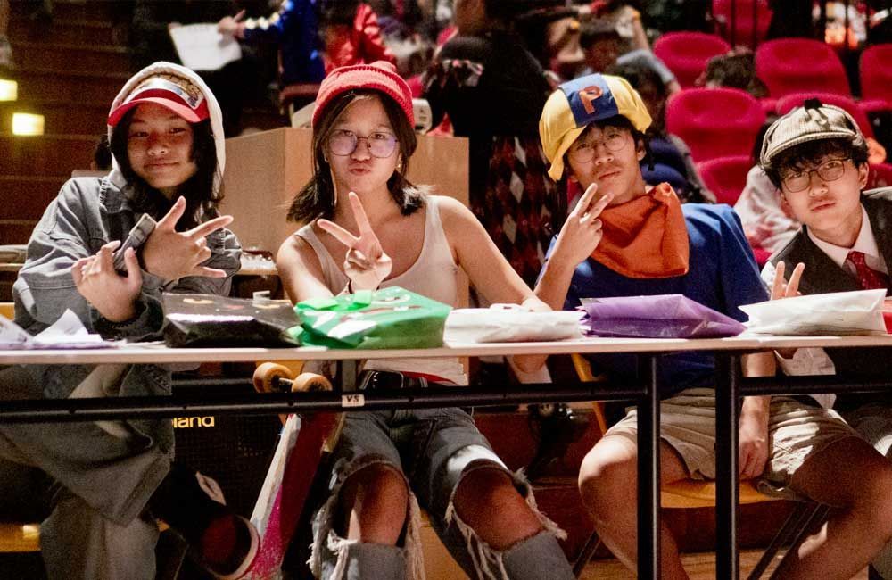 A group of people are sitting at a table giving peace signs.