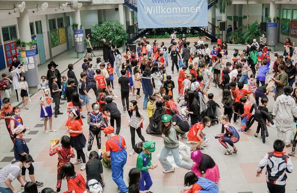 A large group of people dressed in costumes are dancing in front of a stage.