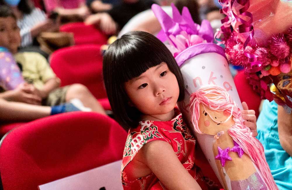 A little girl is holding a stuffed doll in a cone.