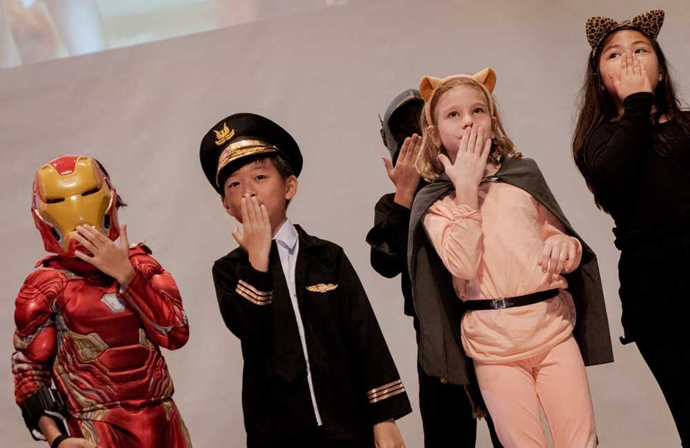 A group of children dressed in costumes are standing next to each other.