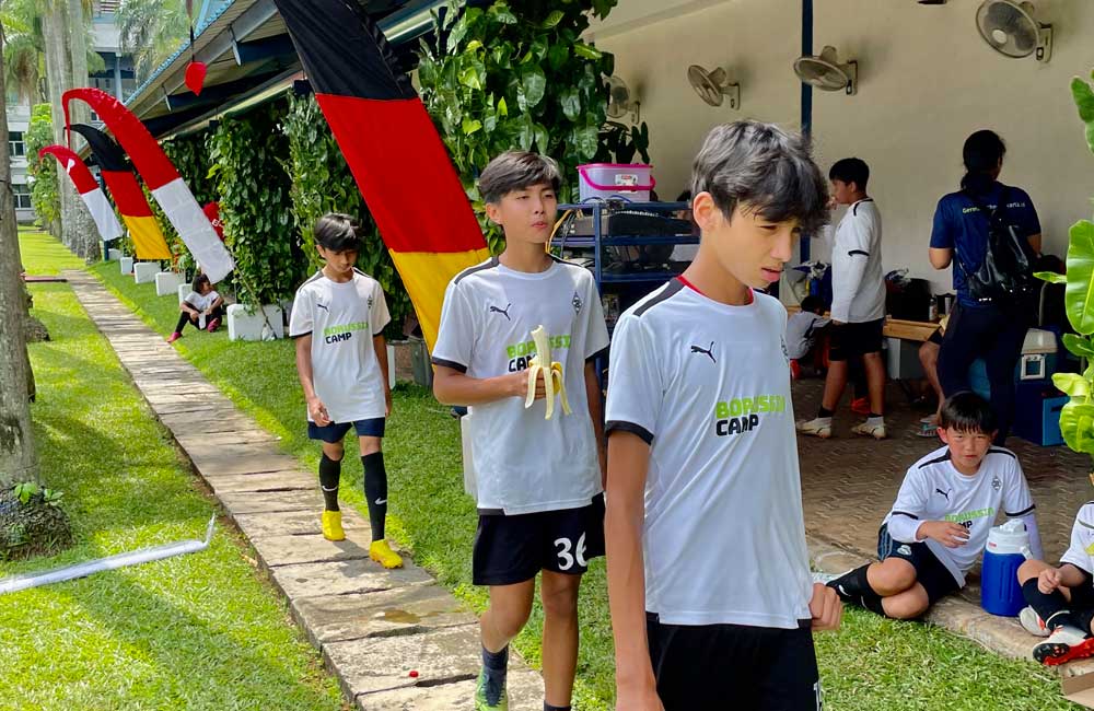 A group of young boys are walking down a sidewalk.