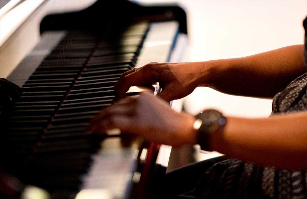 A person wearing a watch is playing a piano