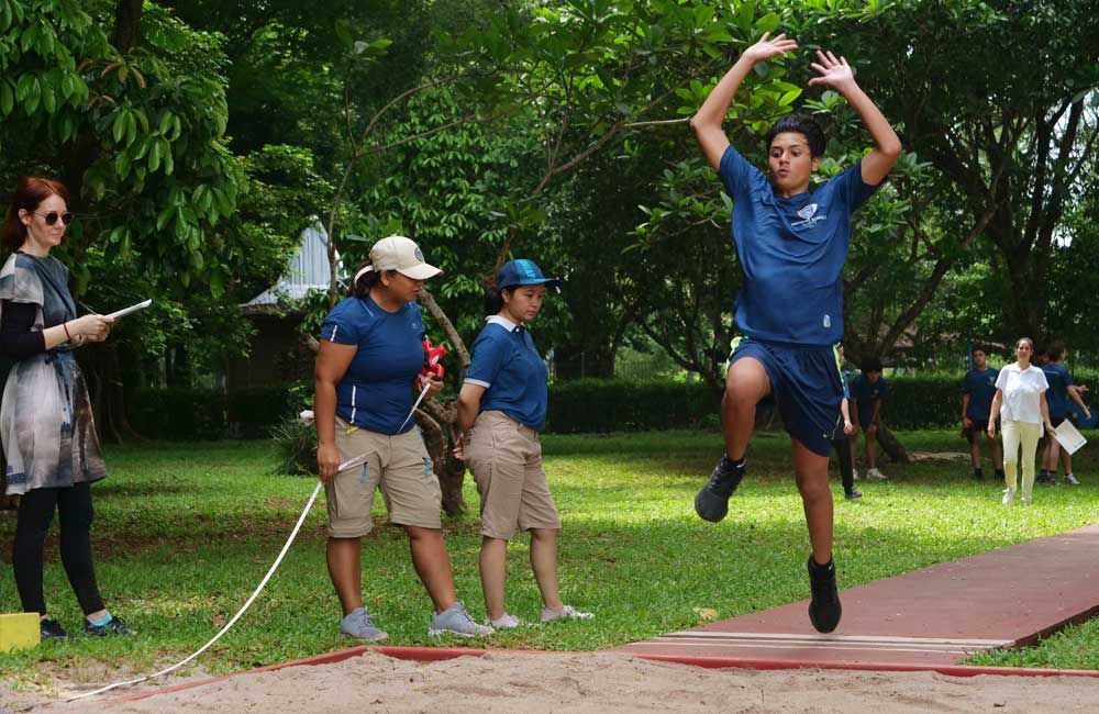 A boy is jumping in the air while a group of people watch.