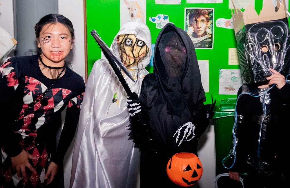 A group of children dressed in halloween costumes are posing for a picture.