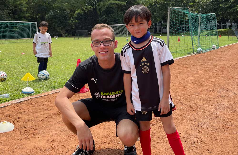 A man and a boy are posing for a picture on a soccer field.
