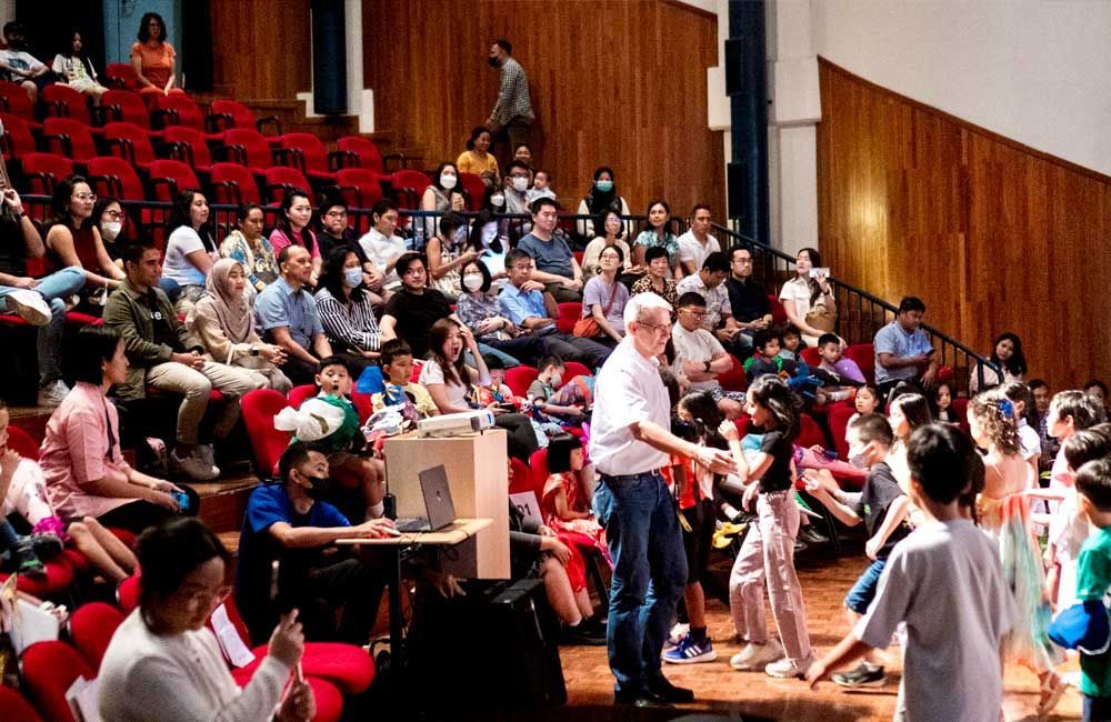 A man is standing in front of a crowd of people in an auditorium.