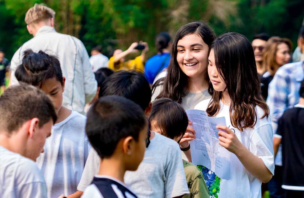 A group of young people are standing in a park talking to each other.