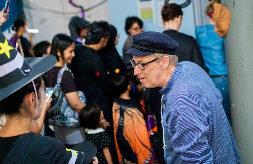 A man wearing a hat and glasses is standing in a crowd of people.