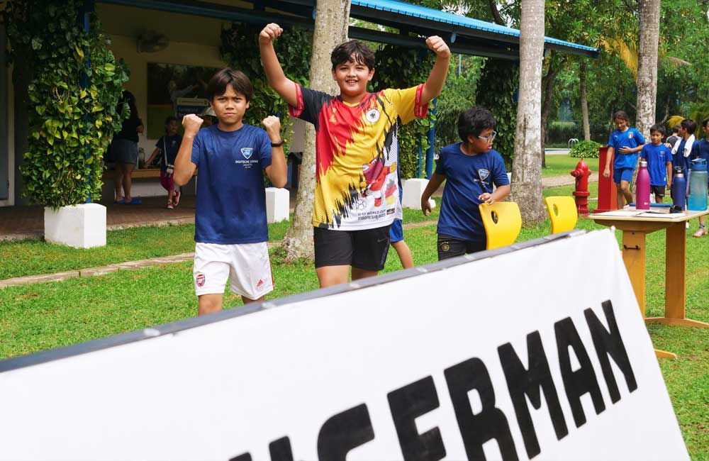 A group of children are standing in front of a sign that says german.