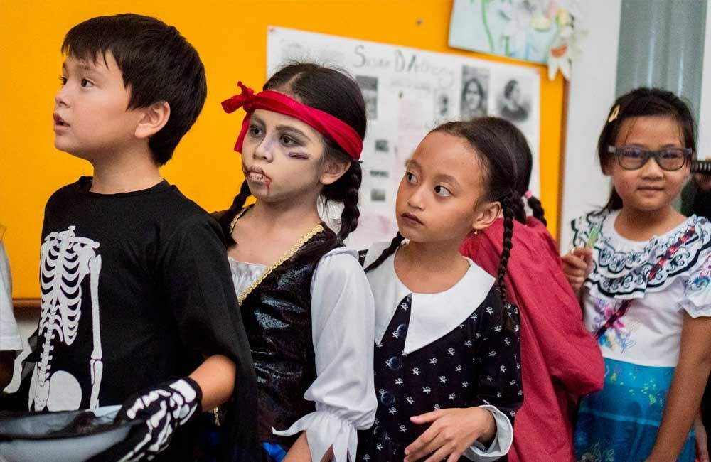A group of children dressed in halloween costumes are standing next to each other.