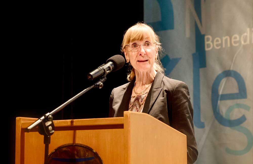 A woman is standing at a podium speaking into a microphone