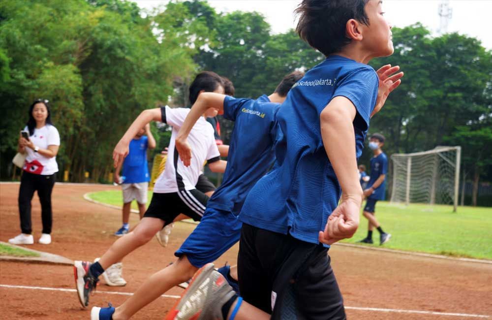 A group of young boys are running on a track.