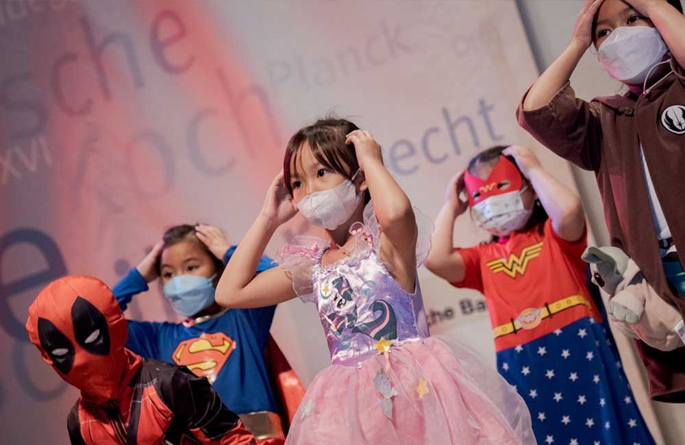 A group of children wearing masks and costumes are standing next to each other.