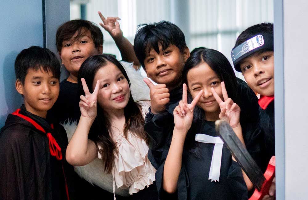 A group of children are posing for a picture and giving peace signs.