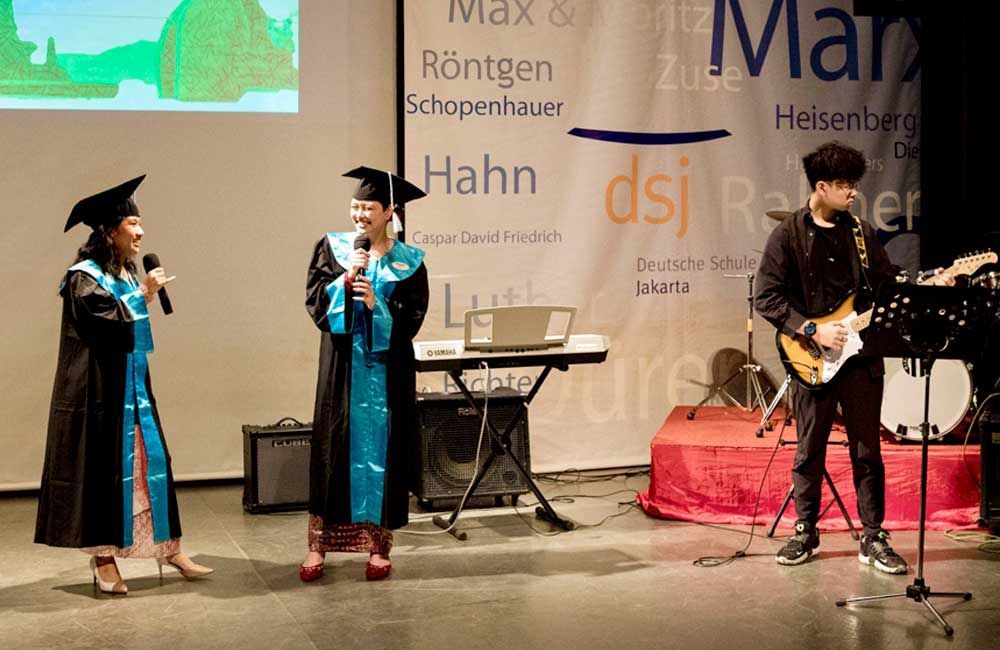 A group of graduates are singing and playing instruments on stage